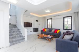 a living room with two blue couches and a tv at Villa Sherbella in Fethiye