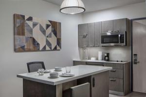 a kitchen with a table and a microwave at Hyatt House Denver Aurora Anschutz Medical Campus in Aurora