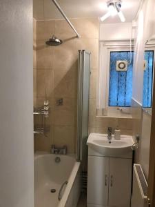 a bathroom with a tub and a sink and a shower at Entire flat, comfortable 2 double bedrooms in Woolwich