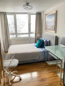 a bedroom with a bed and a desk and window at Entire flat, comfortable 2 double bedrooms in Woolwich