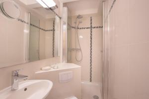 a white bathroom with a shower and a sink at Abaluga 4A in Wenningstedt +22 photos