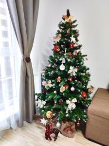 a christmas tree in a living room next to a window at Luxury Mountain View Apartment in Braşov