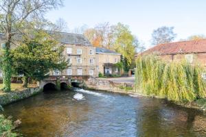 a river in a town with a bridge and buildings at The Old Mill Cottage in Fakenham