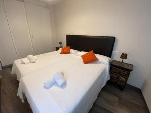 um quarto com 2 camas brancas com almofadas laranjas e brancas em HOSPEDAJE STOP em Corrubedo