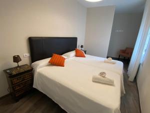 um quarto com uma grande cama branca com almofadas laranja em HOSPEDAJE STOP em Corrubedo