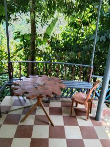 Munnar green portico cottage في مونار: طاولة خشبية ومقعد على أرضية متقاطعة
