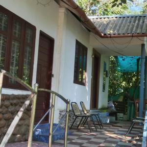 a porch of a house with chairs and a door at Munnar green portico cottage in Munnar