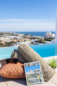 książka i okulary słoneczne siedzące obok basenu w obiekcie Penthouse Lord of Mijas , Sea View 6P, Casa Banderas, D23A w mieście La Cala de Mijas