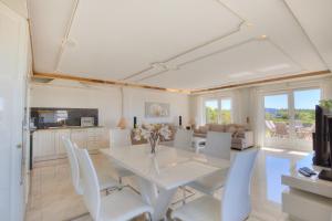 uma sala de jantar branca com uma mesa e cadeiras brancas em Haus am Meer F1 em Wenningstedt