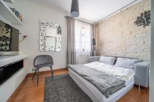 a bedroom with a brick wall and a bed and a chair at Trevilles Apartamenty Mountain View in Szklarska Poręba