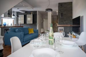 a dining table with wine glasses and a blue couch at Trevilles Apartamenty Mountain View in Szklarska Poręba