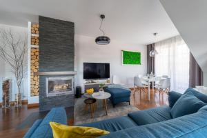 a living room with a blue couch and a fireplace at Trevilles Apartamenty Mountain View in Szklarska Poręba