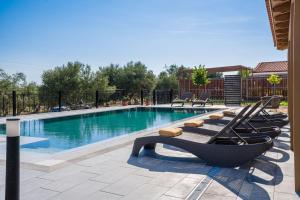 a swimming pool with lounge chairs in front of it at Villa Rudi in Atsoupádhes