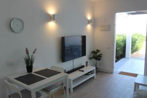 een woonkamer met een tv aan een witte muur bij Pachi Beach Alisios Playa Corralejo in Corralejo