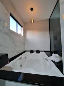 uma grande banheira na casa de banho com uma janela em Villagio da Mantiqueira em Monte Verde
