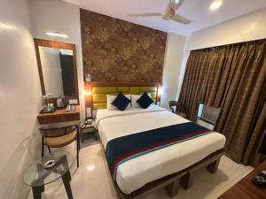 Schlafzimmer mit einem Bett, einem Schreibtisch und einem Spiegel in der Unterkunft SriKrishna Paradise Hotel Thane Navi Mumbai in Thane
