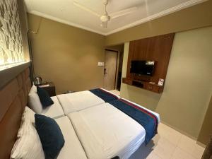 ein Hotelzimmer mit einem Bett und einem TV in der Unterkunft SriKrishna Paradise Hotel Thane Navi Mumbai in Thane