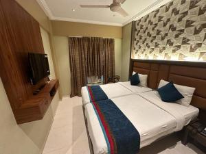 a bedroom with a large bed and a television at SriKrishna Paradise Hotel Thane Navi Mumbai in Thane