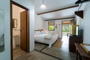 a bedroom with a bed and a bathroom with a tub at Pousada Caraiva Guest House in Caraíva