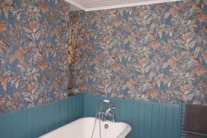 La salle de bains est pourvue de papier peint bleu et orange et d'une baignoire. dans l'établissement Brownlow Townhouse 3 bedroom ideal for contractors and visitors, à Lurgan