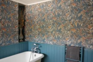 La salle de bains est pourvue d'une baignoire et de papier peint bleu et orange. dans l'établissement Brownlow Townhouse 3 bedroom ideal for contractors and visitors, à Lurgan