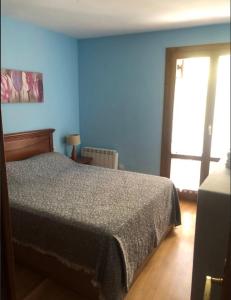 1 dormitorio con cama y pared azul en Casa Rincón de Broto en Broto