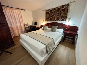 1 dormitorio con 1 cama blanca grande y escritorio en Hotel S'Ortale en Orosei