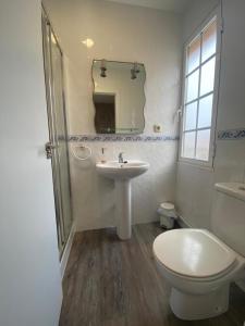 a bathroom with a sink and a toilet and a mirror at HOSPEDAJE STOP in Corrubedo