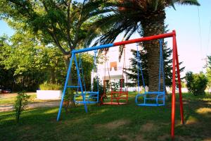 ein Spielplatz in einem Park mit einer Palme in der Unterkunft Simplicity at Iris Accommodation Adults only in Psakoudia