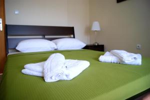 zwei Stapel Handtücher auf einem grünen Bett in der Unterkunft Simplicity at Iris Accommodation Adults only in Psakoudia