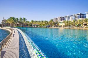 una piscina en un complejo con palmeras y edificios en Reef Boutique Hotel, en Manama