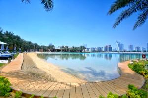 a large pool with a wooden boardwalk next to a city at Palavra Resort in Manama