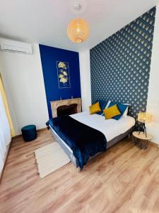 a bedroom with a large bed with a blue wall at Chaleureux T2 proche gare in Bourgoin
