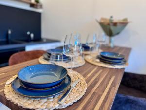 a wooden table with plates and wine glasses on it at Chaleureux T2 proche gare in Bourgoin +15 photos