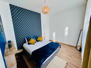 um quarto com uma cama com lençóis azuis e almofadas amarelas em Chaleureux T2 proche gare em Bourgoin