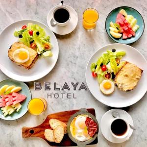 une table avec des assiettes de nourriture et des tasses de café dans l'établissement Belaya Hotel, à Jepara