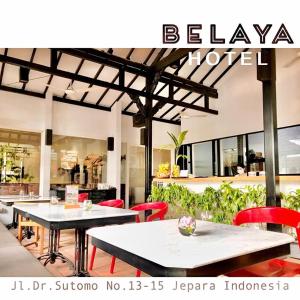 a restaurant with two tables and red chairs at Belaya Hotel in Jepara