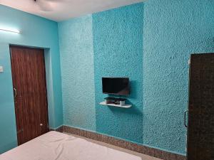 ein Schlafzimmer mit einer blauen Wand und einem TV darauf in der Unterkunft New Ananda lodge in Vriddhāchalam