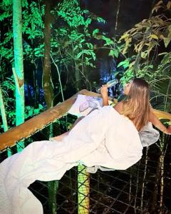 una mujer tumbada en un banco en la jungla en TreeHouse Seu Paraíso nas Montanhas en Marechal Floriano