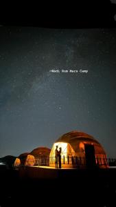 a couple of people standing in front of domes under the stars at Wadi Rum Mars Camp in Wadi Rum