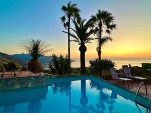 una piscina con palmeras y una puesta de sol en VILLA LOU TAORMINA Exclusive Use of Pool en Taormina