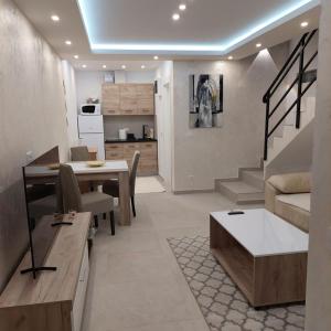 a living room with a dining table and a kitchen at Apartman LUX Jelena in Surčin
