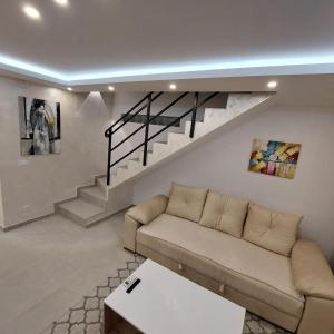 a living room with a couch and a staircase at Apartman LUX Jelena in Surčin