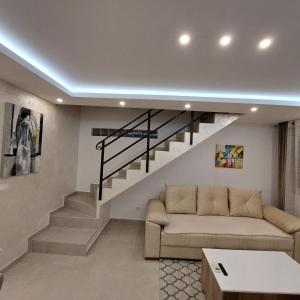 uma sala de estar com um sofá e escadas em Apartman LUX Jelena em Surčin