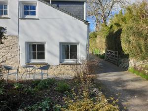 a white house with two chairs in front of it at Primrose Cottage in Helston