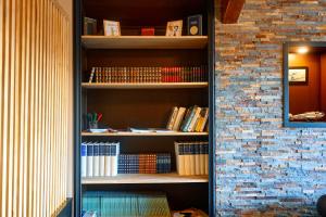 une étagère remplie de livres à côté d'un mur de briques dans l'établissement Logis Clermotel - Hôtel & Restaurant, à Agnetz