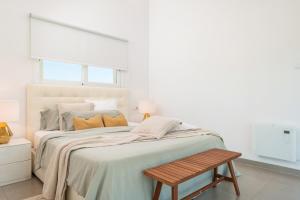 a white bedroom with a large bed and a wooden bench at Casa Blanca in Sencelles +21 photos