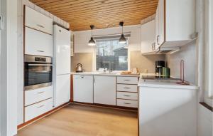Il comprend une cuisine avec des placards blancs et un plafond en bois. dans l'établissement Cozy Home In ster Assels With Sauna, à Øster Assels