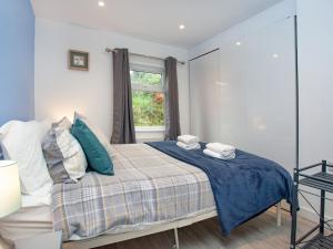 1 dormitorio con cama con sábanas azules y ventana en Meadow View - Uk44608, en Carnbrea
