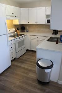 a kitchen with white cabinets and a trash can at Freshly Updated 3 Bedroom Townhome in Lethbridge